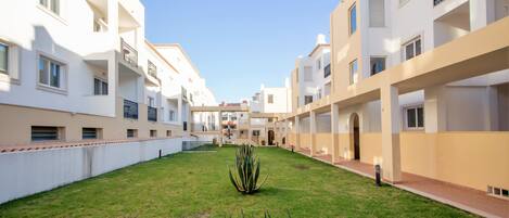 A courtyard with a central grassy area, surrounded by multi-story buildings with balconies and windows.
