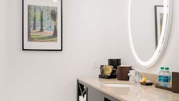 Une salle de bain avec un tableau encadré, un miroir, un lavabo et des articles de toilette.