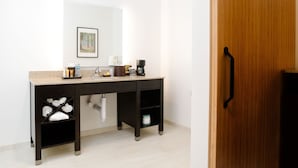 Ein modernes Badezimmer mit einem dunklen Holz-Waschtisch, einem Waschbecken und einem Spiegel. Auf dem Waschtisch liegen Handtücher und Toilettenartikel, und ein WC ist unter dem Waschbecken sichtbar.