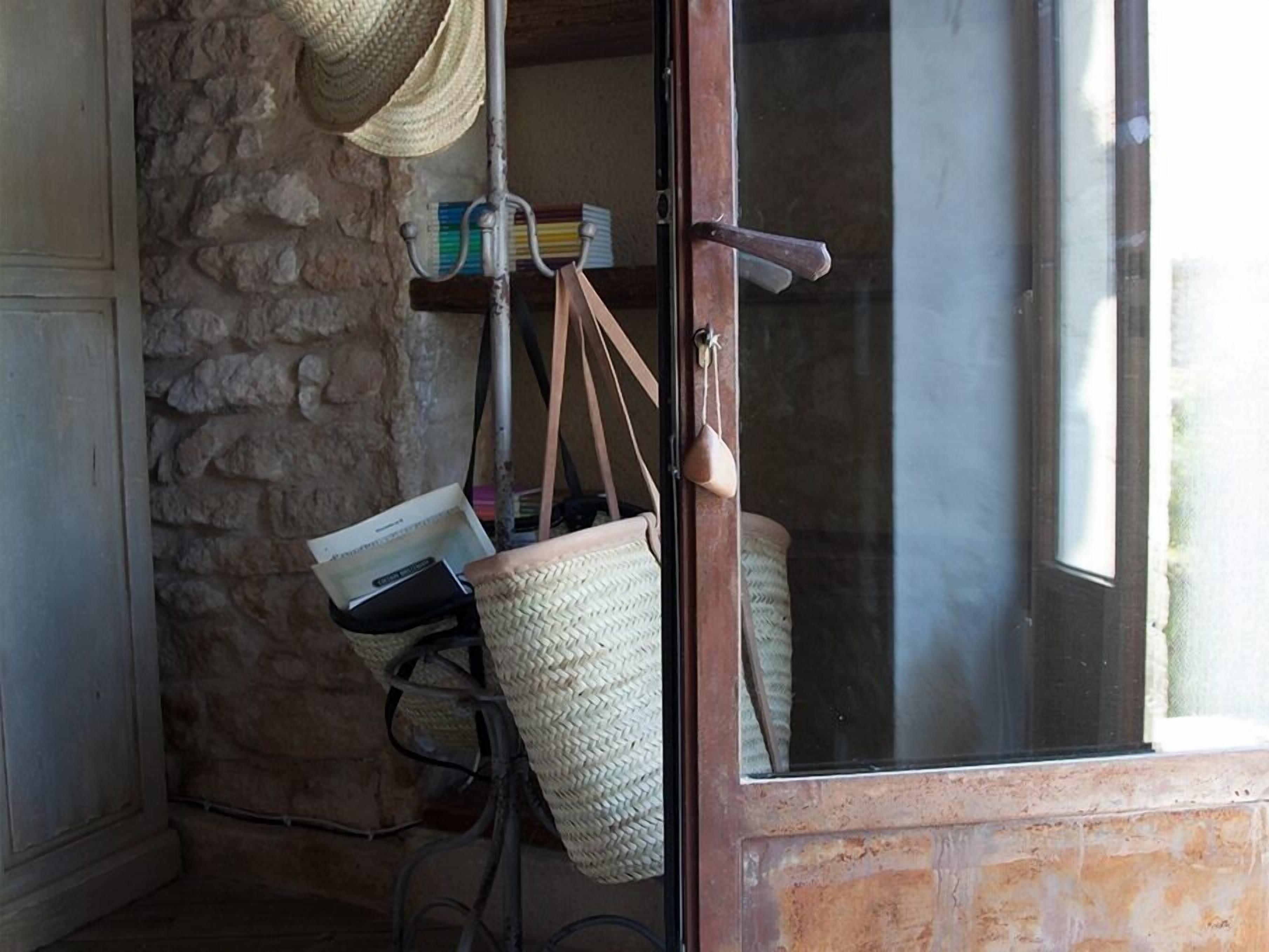 A rustic interior with a stone wall, a wooden door, and a wicker basket.