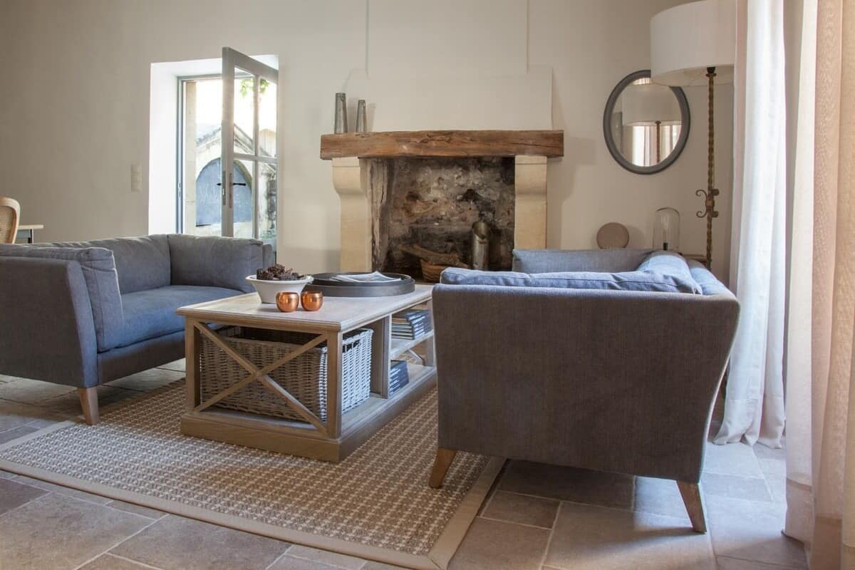 Un salon avec une cheminée, deux canapés, une table basse et une lampe.
