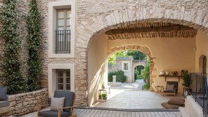 An outdoor patio area with stone walls, a wooden bench, a chair, and a small table.
