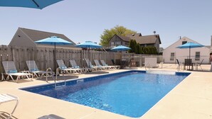 Ein rechteckiger Pool mit Fliesen umgeben, mit Liegestühlen und Sonnenschirmen.