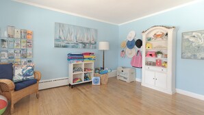 Ein Zimmer mit blauer Wand, einem Korbstuhl, einem Bücherregal und einer Lampe.