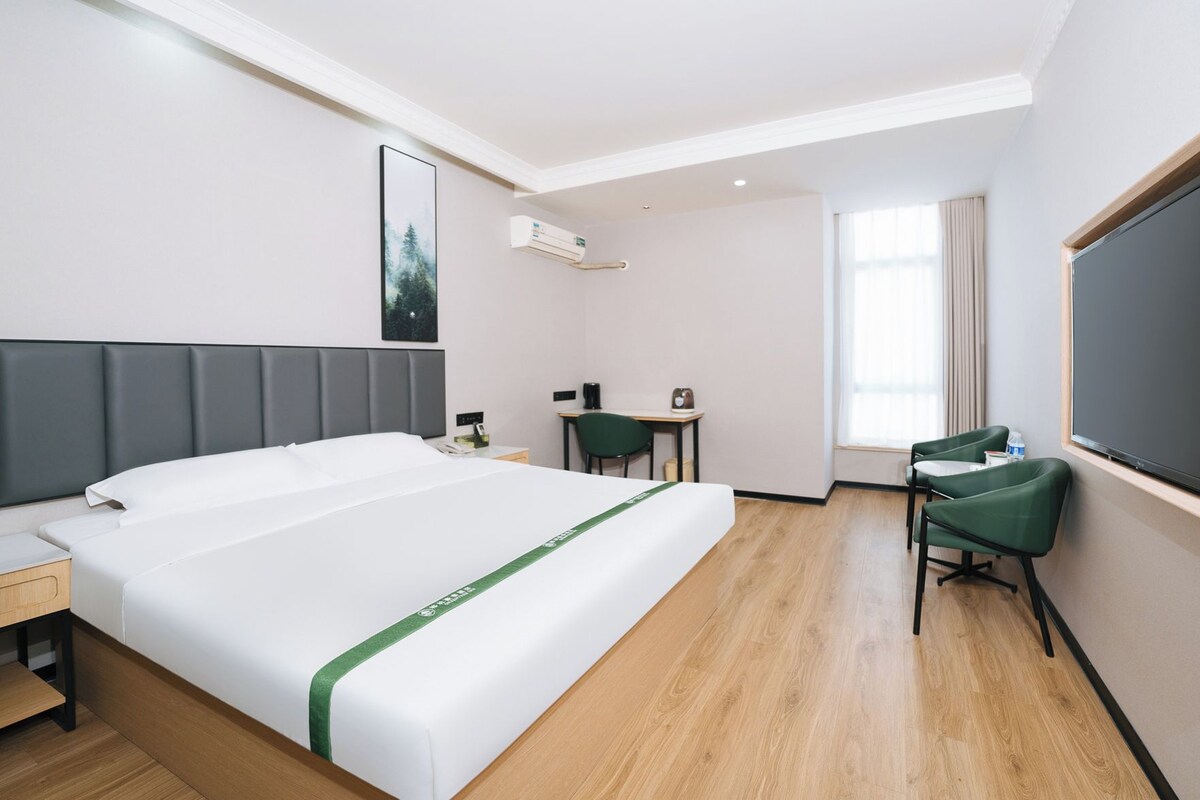 A hotel room with a bed, a desk, a chair, and a large window.