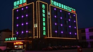 Un hôtel à l’architecture moderne, doté d’une enseigne lumineuse au néon et d’un parking.