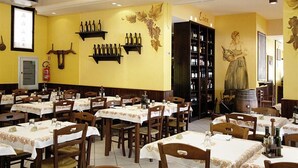 A restaurant with tables set for dining, wine bottles on shelves, and a mural on the wall. - Residence La Nona (Cervia)