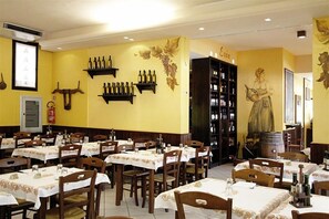 Ein Restaurant mit mehreren Tischen, Stühlen und Weinflaschen auf Regalen.