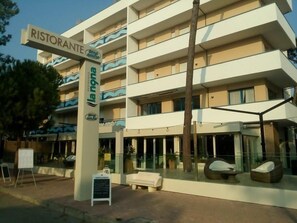 Ein mehrstöckiges Hotel mit Restaurantschild, Außenbereich und modernem Design.
