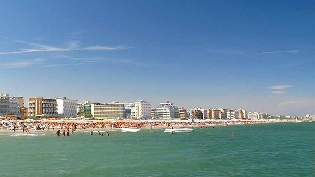 A coastal cityscape with a beach, buildings, and boats. - Residence La Nona (Cervia)