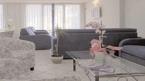 A modern living room with a sofa, a glass coffee table, and a potted plant. - Residence La Nona (Cervia)