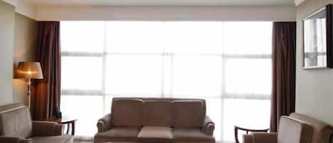 A hotel room with a sofa set, a coffee table, and a lamp.