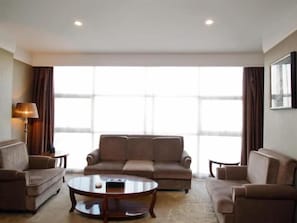 A hotel room with a sofa set, a coffee table, and a lamp.
