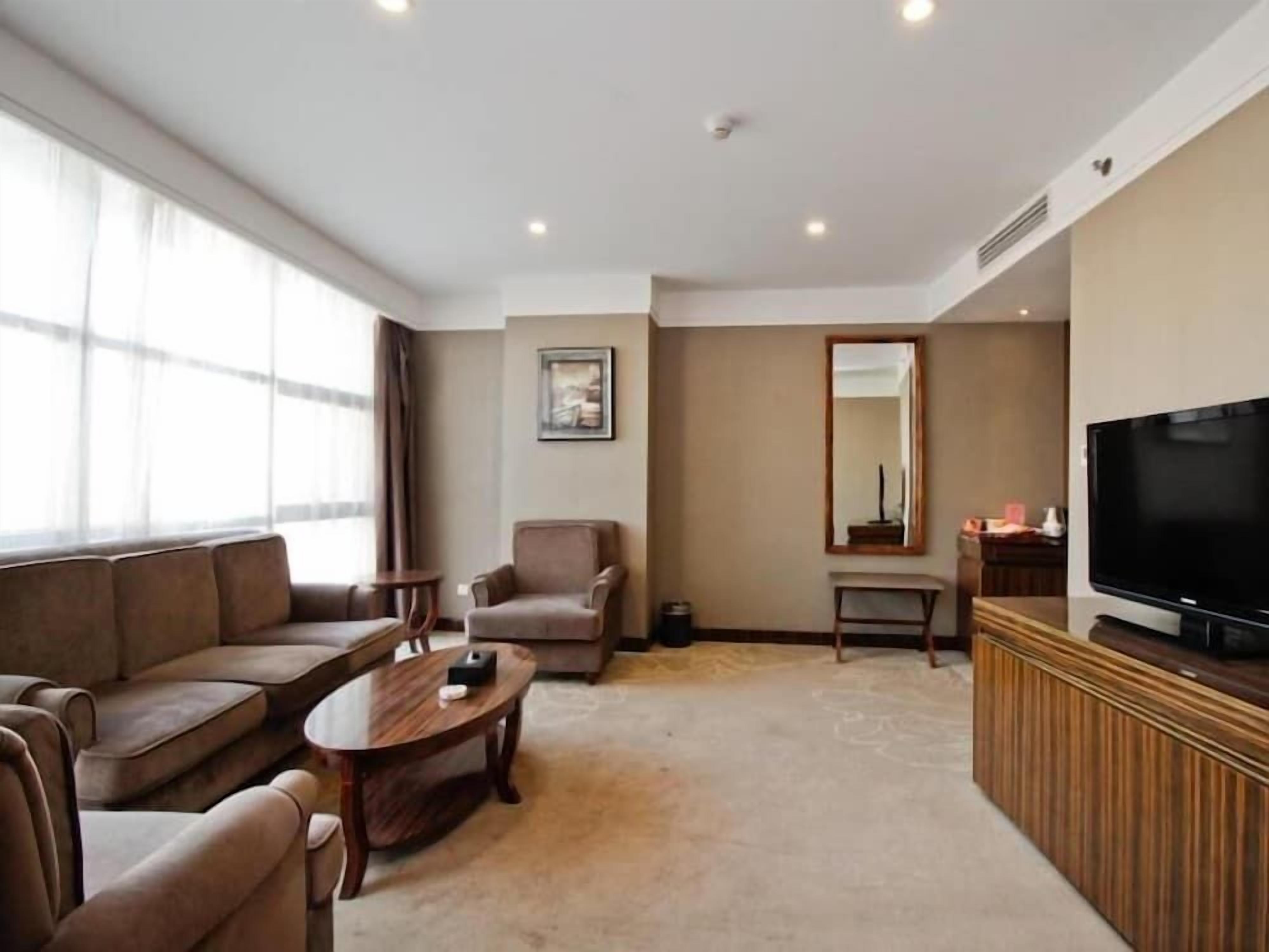 A modern living room with a sofa set, a coffee table, a television, and a large window.
