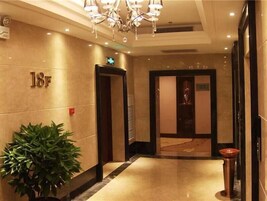 Un vestíbulo de hotel con piso de mármol, una planta en maceta, un candelabro y un letrero que indica la habitación 18F.