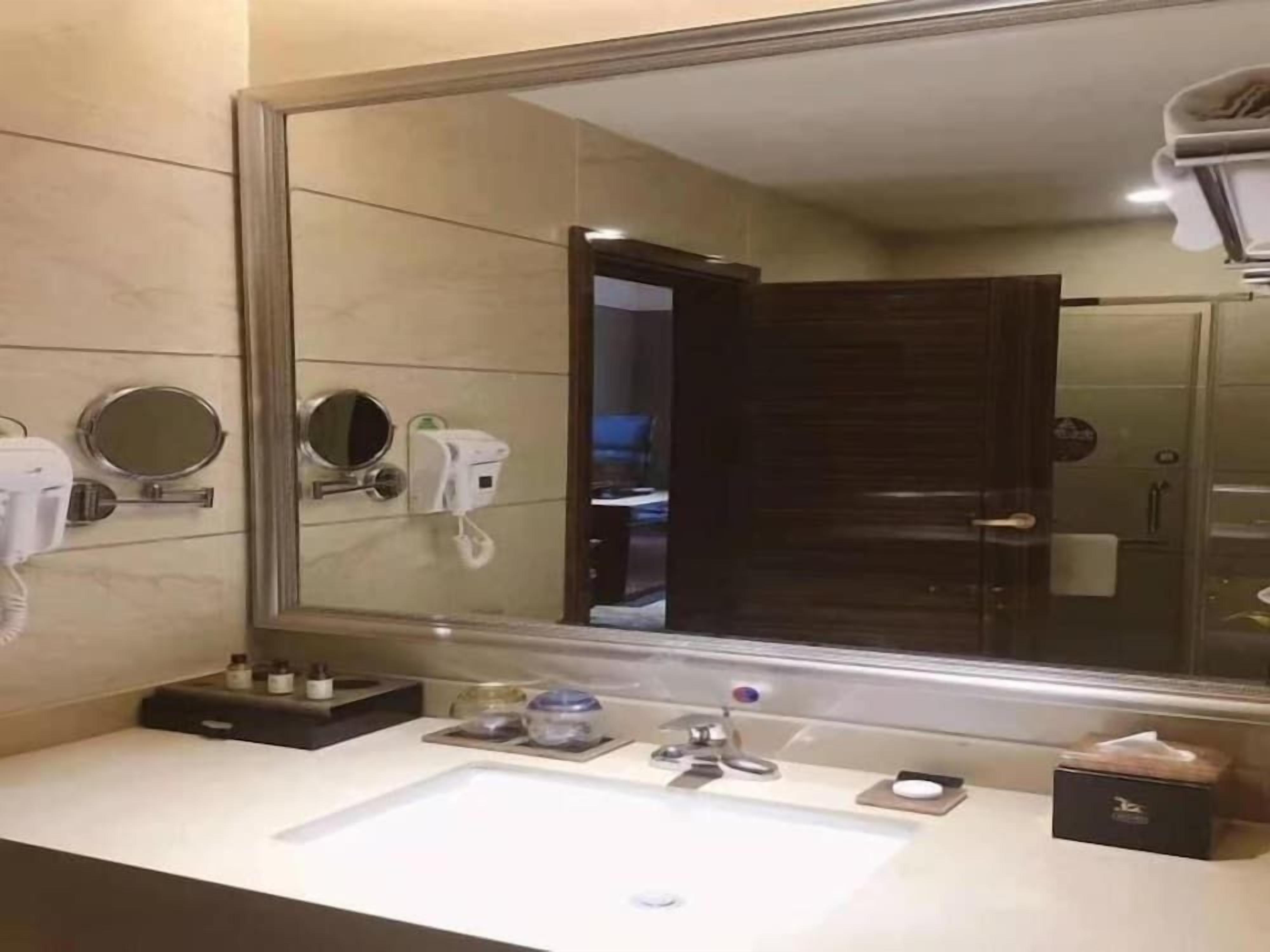 Un bagno moderno con uno specchio grande, un lavandino e un asciugacapelli.