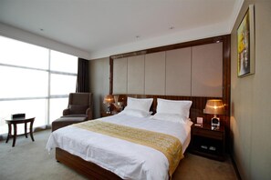 A hotel room with a large bed, a chair, a small table, and a nightstand with lamps. - Greentree Eastern Huainan Guangchang Road Hotel (Huainan)