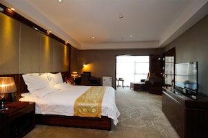 Una habitación de hotel con una cama grande, un televisor, un escritorio y una silla.