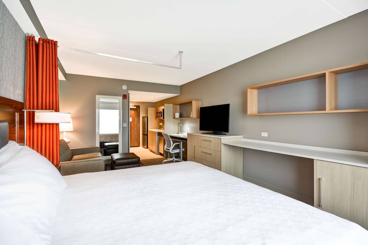 Ein Hotelzimmer mit Bett, Schreibtisch, Stuhl, Fernseher und Kleiderschrank.