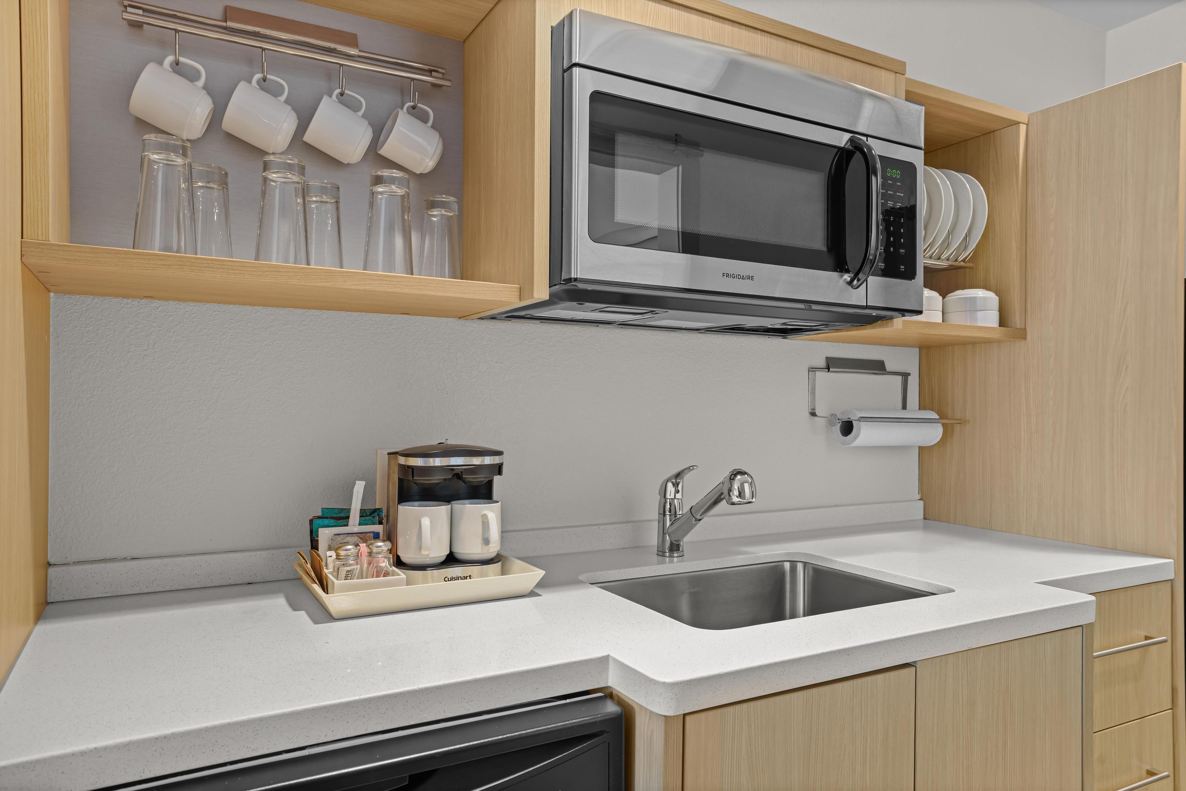 A modern kitchen with a stainless steel microwave, a coffee maker, and a sink.