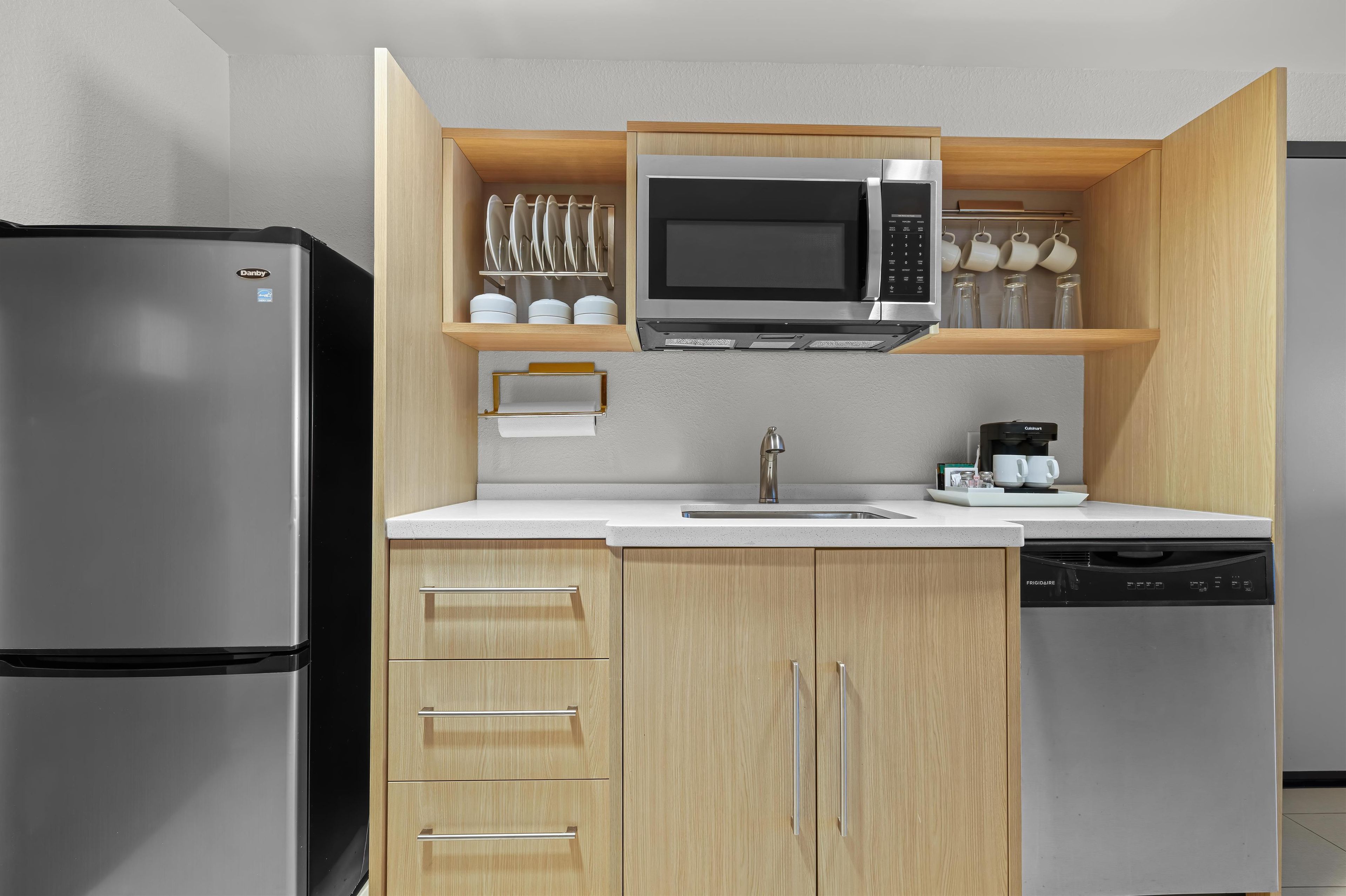 A compact kitchen with a stainless steel refrigerator, a microwave, and a dishwasher.