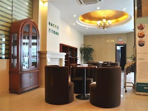 Experience a warm and inviting lobby with traditional charm and modern touches, featuring a classic cabinet, comfortable seating, and an elegant chandelier.