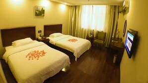 Hotelkamer met twee bedden, een bureau, een stoel, een televisie en een raam met gordijnen.