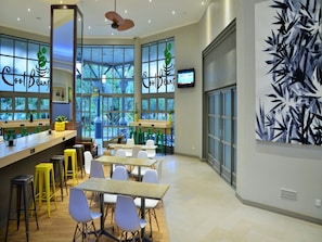 A modern cafe interior with a bar area, seating, and large windows. - Cresta Lodge Harare (Harare)