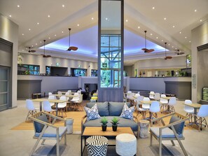 A spacious lobby with a high ceiling, multiple seating areas, and a central column. - Cresta Lodge Harare (Harare)