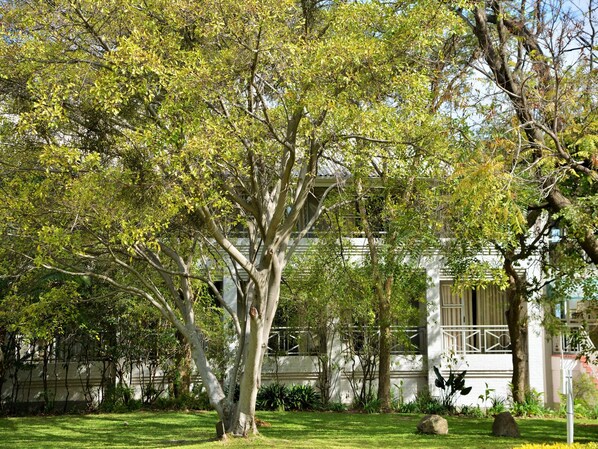 Un bâtiment à l’extérieur blanc, entouré d’une pelouse bien entretenue et d’arbres.
