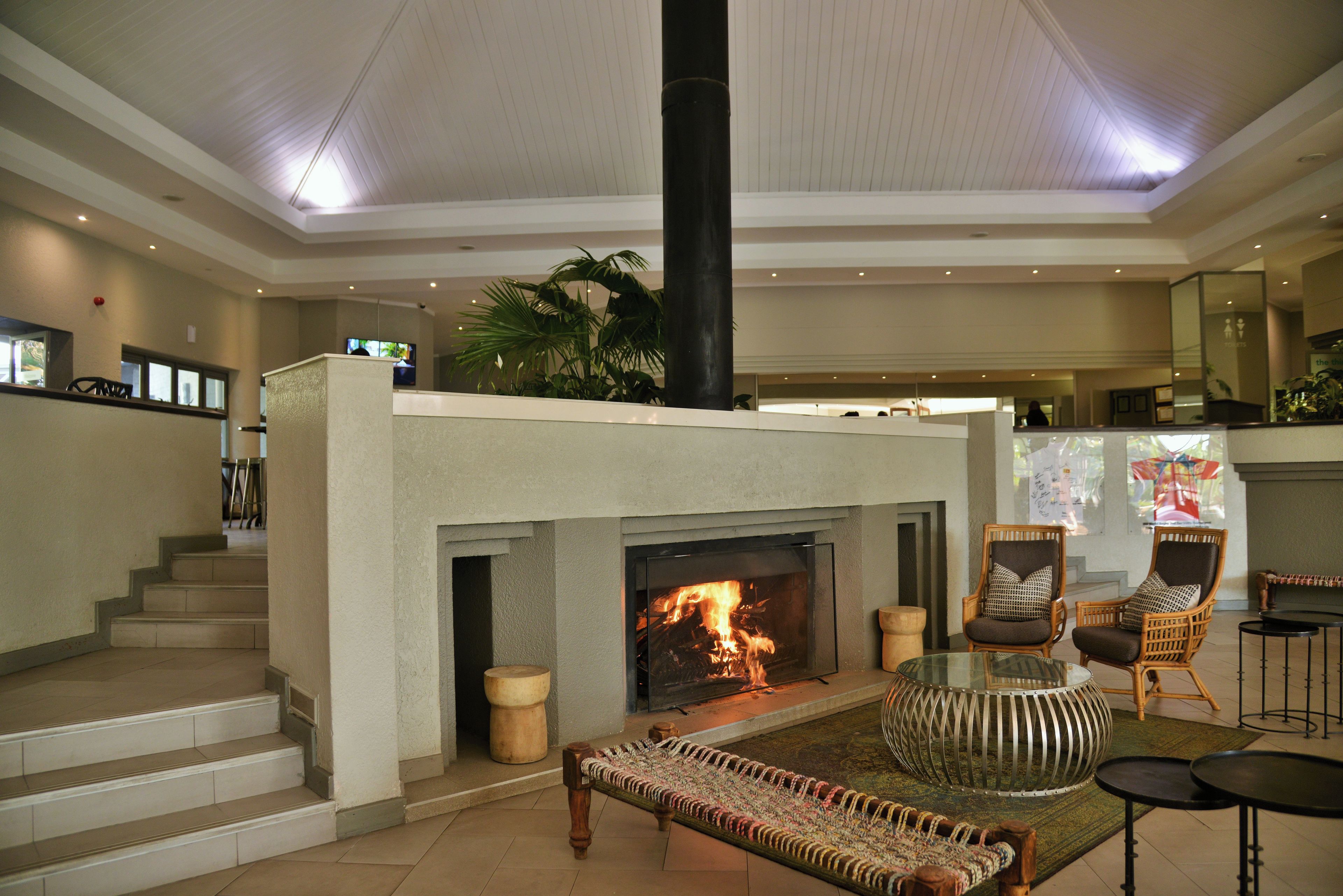 Un vestíbulo amplio con chimenea, zona de estar y una escalera que conduce a plantas superiores.