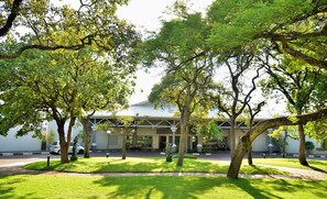 A building with a covered entrance, surrounded by trees and a well-maintained lawn.