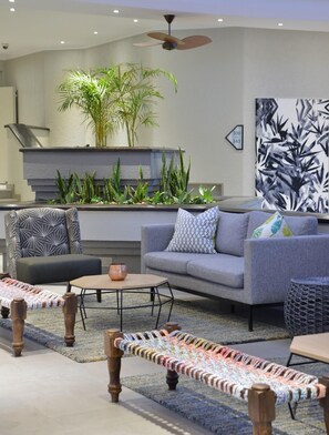 A modern living room with a grey sofa, patterned armchairs, a coffee table, and a decorative rug.