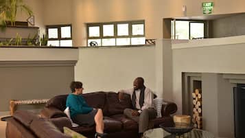 A lounge area with leather sofas, a glass coffee table, and a fireplace.