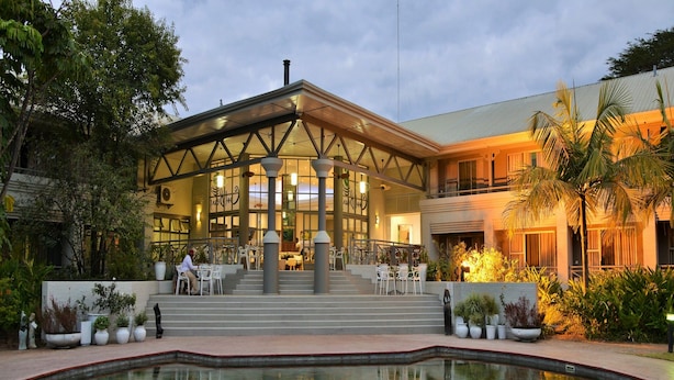 Een hotel met een zwembad, terras en een overdekt gedeelte met een trap naar de ingang.
