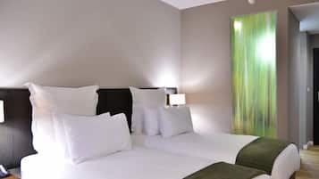 A hotel room with a large bed, two bedside tables, and a green abstract painting on the wall.