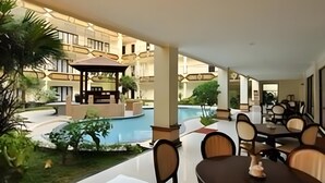 A hotel courtyard with a pool, outdoor seating, and a gazebo. - Yusro Hotel Convention (Peterongan)