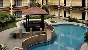 A swimming pool with a gazebo, surrounded by a building with balconies and a landscaped garden. - Yusro Hotel Convention (Peterongan)