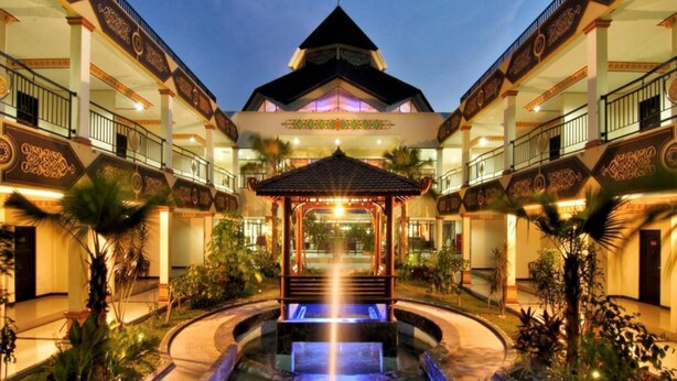 A hotel courtyard with a central water feature, surrounded by balconies and tropical plants. - Yusro Hotel Convention (Peterongan)