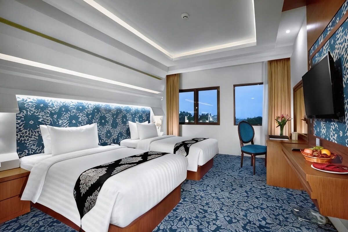 Une chambre d’hôtel avec un grand lit, un bureau, une chaise et un téléviseur.