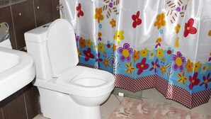 Ein Badezimmer mit Toilette, Badewanne und einer Duschvorhang mit floralem Muster.