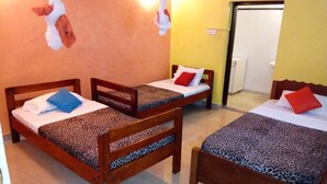 Ein Zimmer mit drei hölzernen Betten, jeweils mit einer Bettdecke mit Leopardenmuster und einem Kopfkissen.