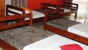 Une chambre avec trois lits en bois, chacun ayant un style de matelas et d’oreiller différent.