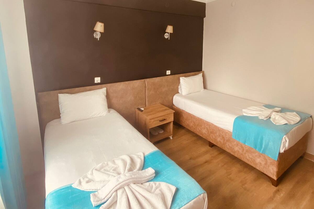 Une chambre d’hôtel avec deux lits, une table de chevet et un luminaire au plafond.