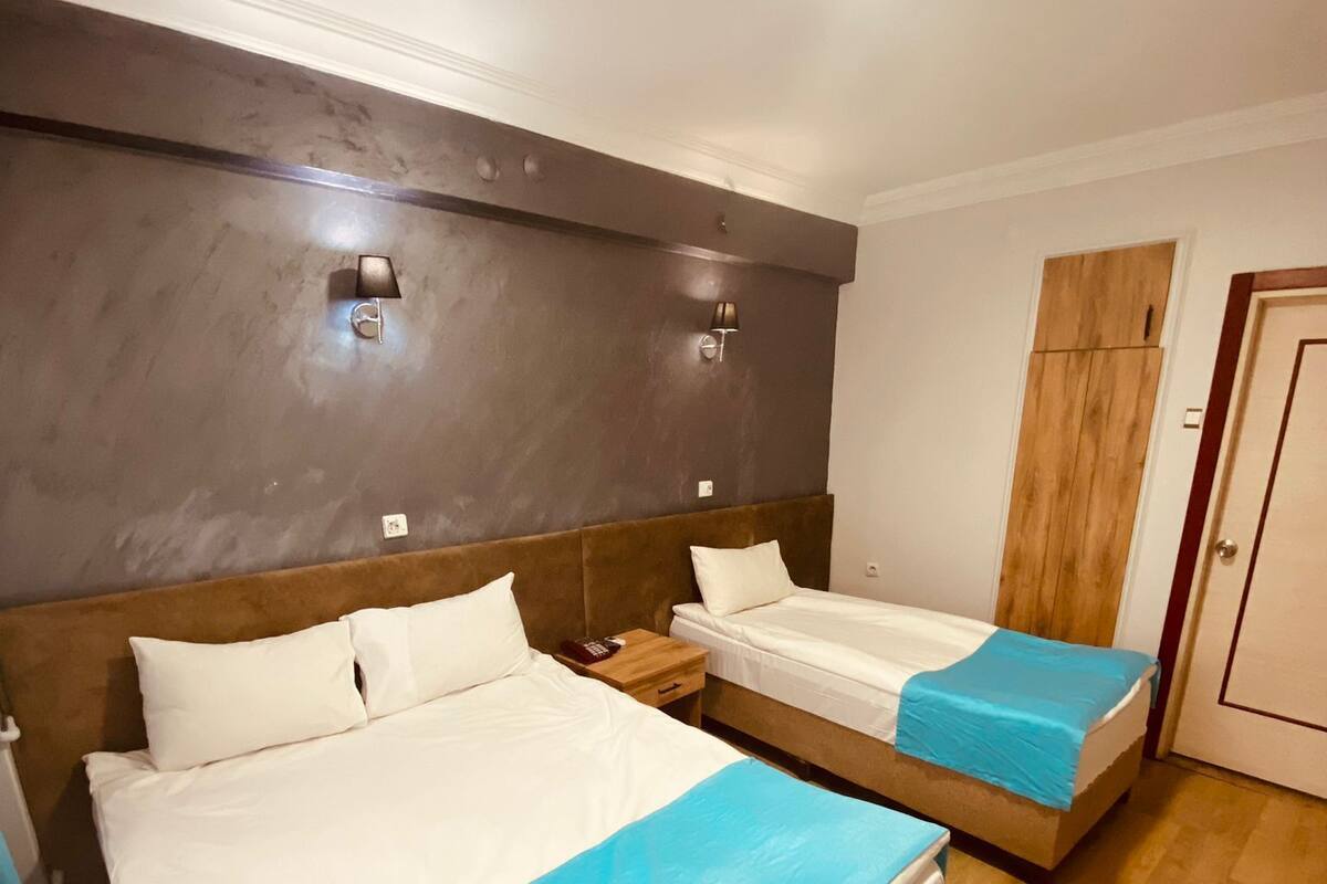 Une chambre d’hôtel avec deux lits, une armoire en bois et une table de chevet avec une lampe.