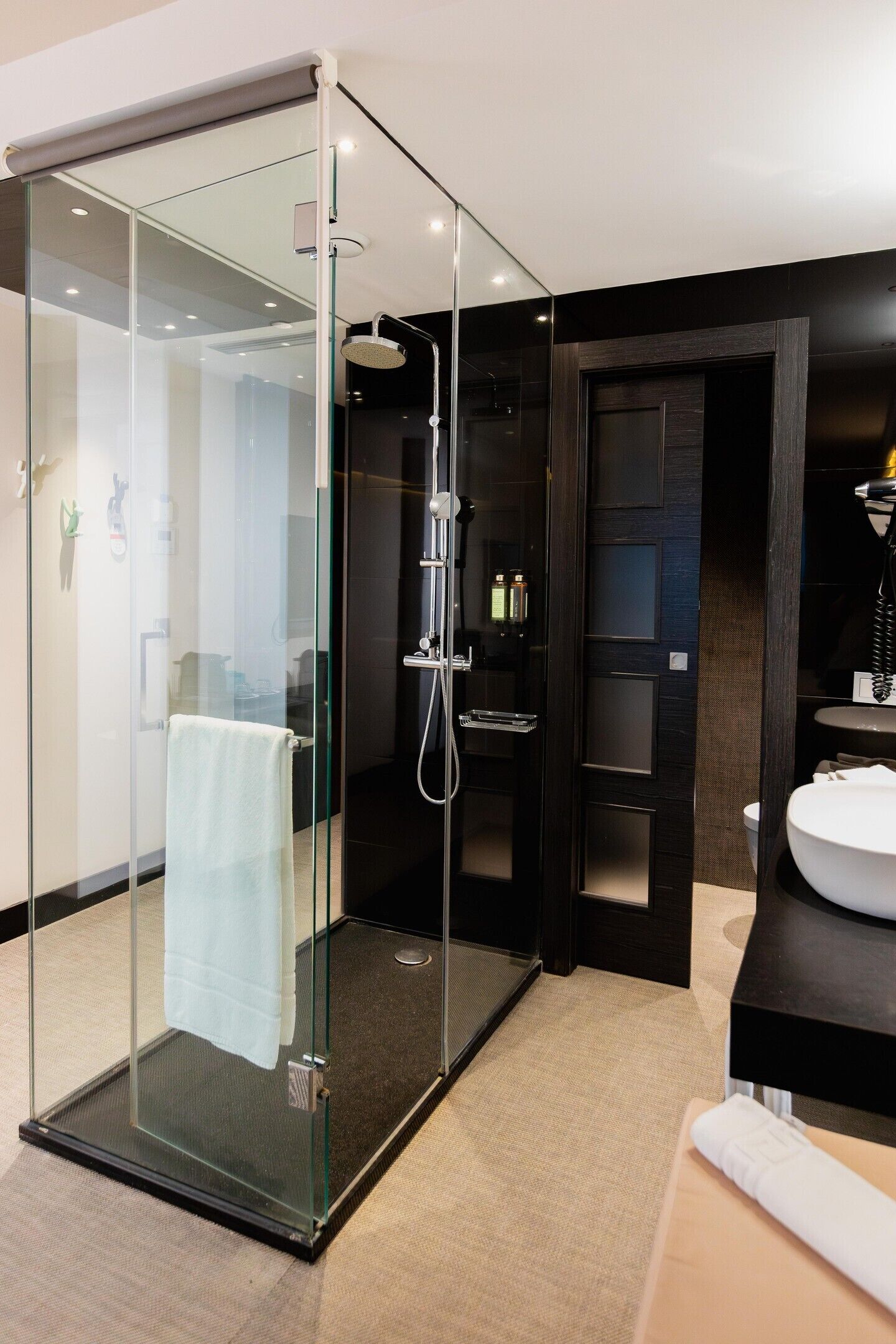 A modern bathroom with a glass-enclosed shower, a white sink, and dark wood cabinetry.