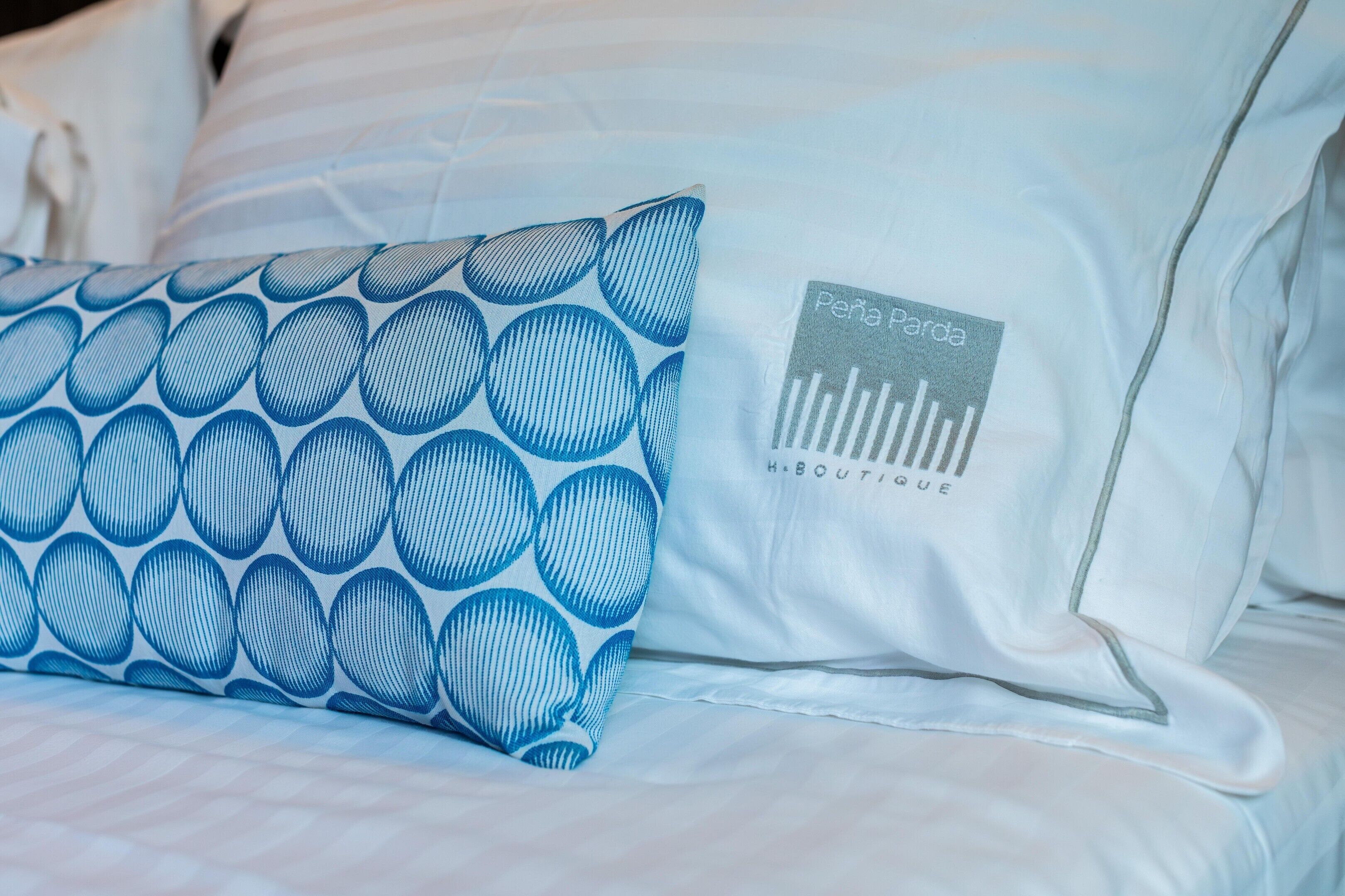 Una cama con un cojín estampado y un cojín con logotipo.