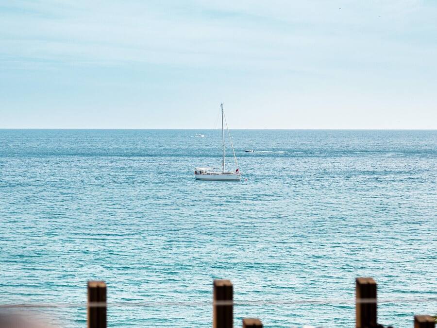 Vista del mar con un velero y un bote más pequeño a lo lejos.
