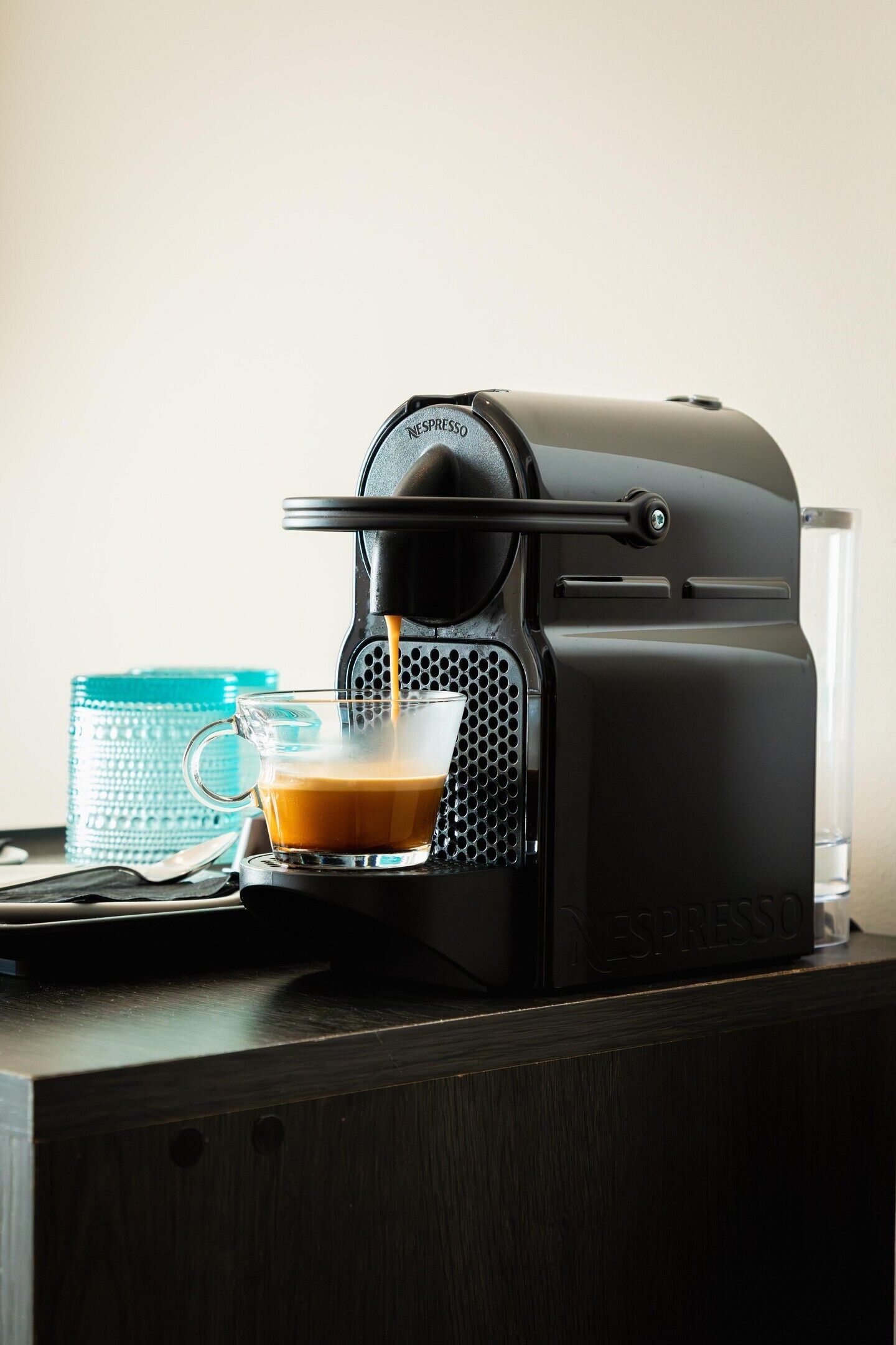 A Nespresso coffee machine dispensing coffee into a clear glass cup.