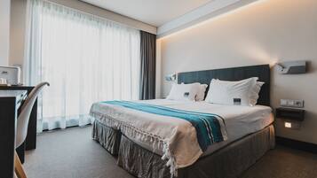 Een hotelkamer met een groot bed, een bureau en een stoel.
